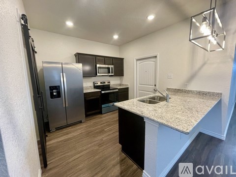 A kitchen with a refrigerator, microwave, oven, and sink.