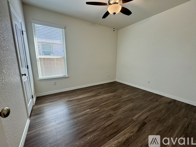 A room with a ceiling fan and wooden flooring.