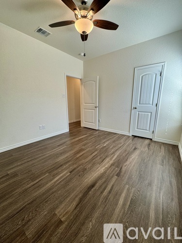 A room with a ceiling fan and wooden flooring.