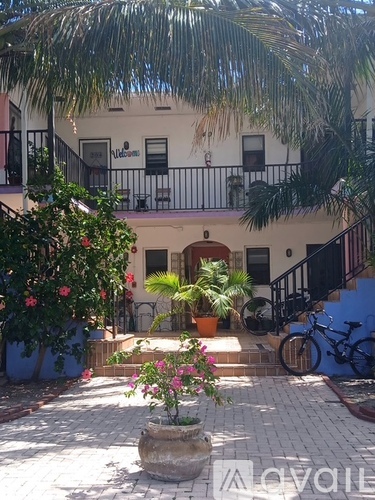 A white building with a balcony and a bicycle parked in front.