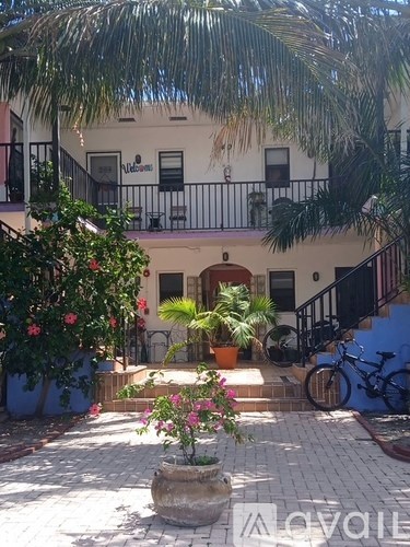 A white building with a balcony and a bicycle parked in front.