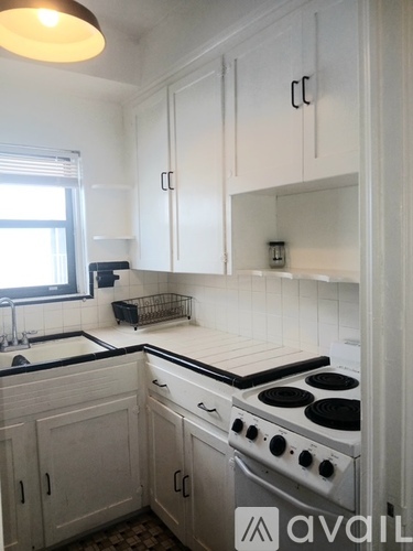A kitchen with white cabinets and a stove top oven.