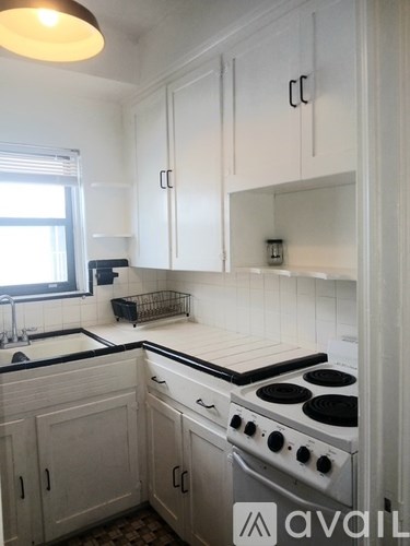 A kitchen with white cabinets and a stove top oven.