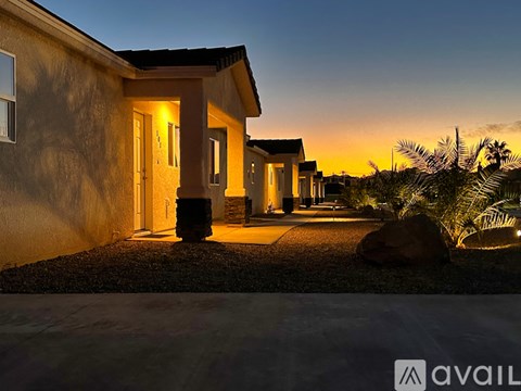 A house with a lit up entrance and a large rock in front of it.