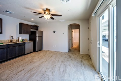 A spacious kitchen with dark brown cabinets and a black refrigerator.