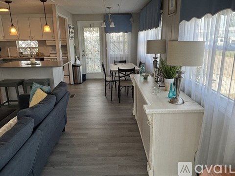 A living room with a blue couch and a dining table with chairs.
