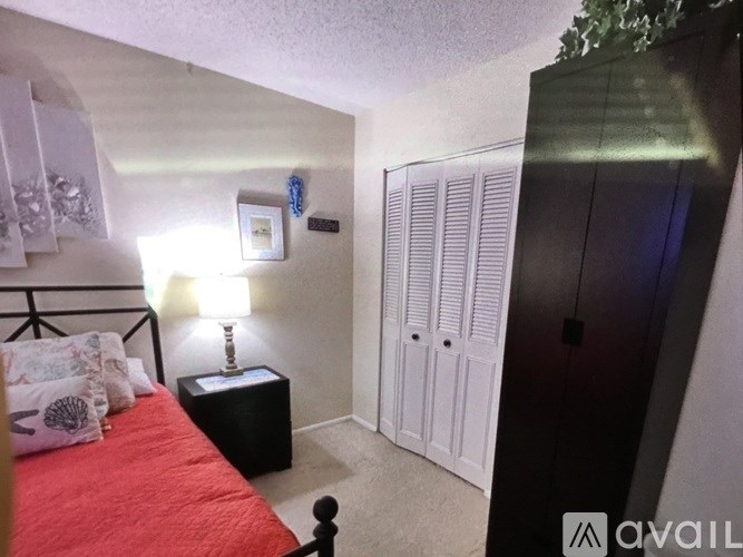 A bedroom with a red bed, a black nightstand, and a white wardrobe.