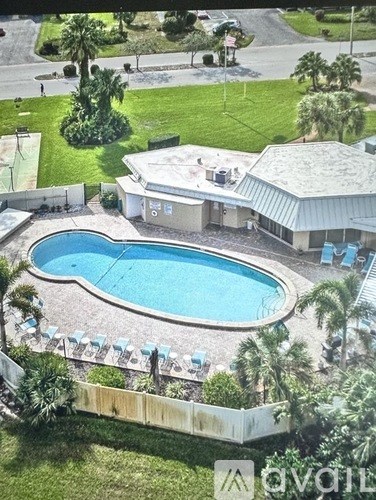 A pool surrounded by a white fence and palm trees.