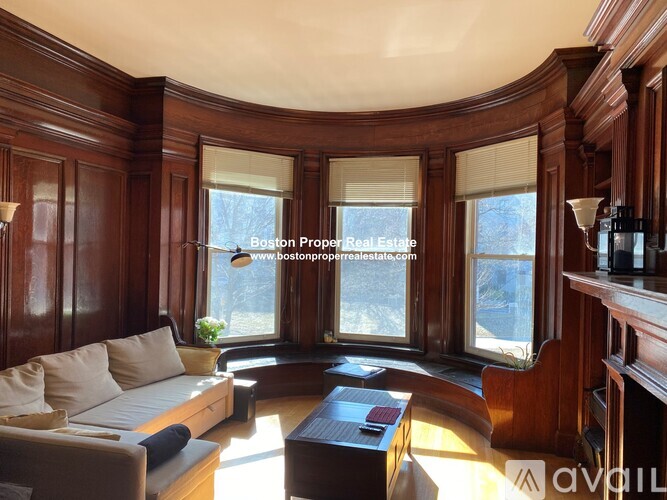 A living room with wood paneling and a large window.