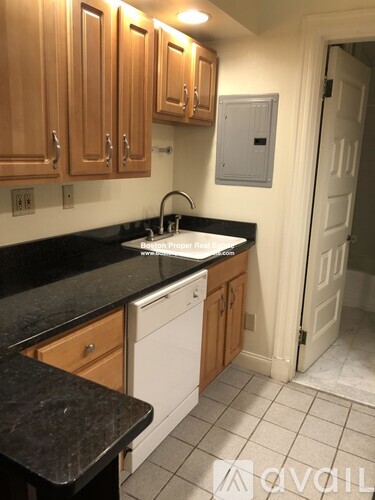 A kitchen with wooden cabinets and a black counter top.