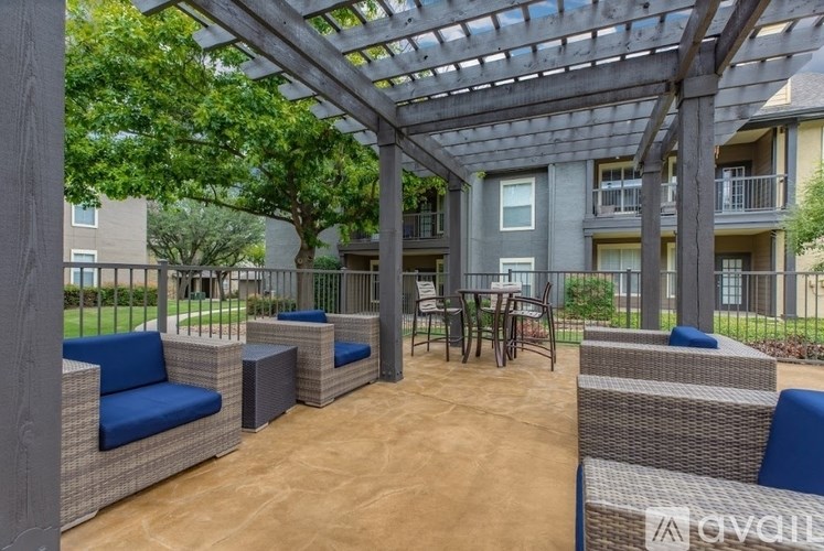 A patio with a pergola and wicker furniture.
