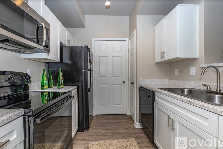 A kitchen with white cabinets and a black refrigerator.