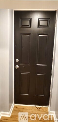 A black door with a silver handle and a small window on the right side.