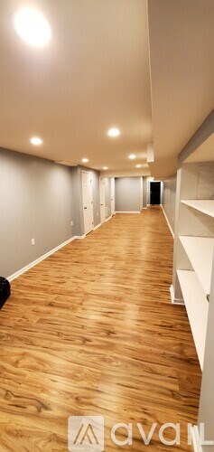 A long hallway with wooden floors and white walls.