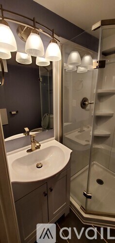 A bathroom with a sink, mirror, and shower.