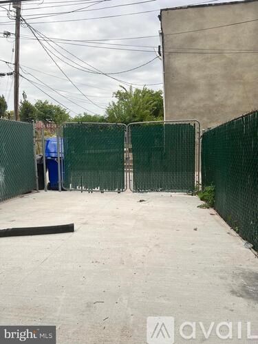 A green fenced area with a blue dumpster in the background.