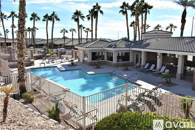 A pool surrounded by palm trees and a building.