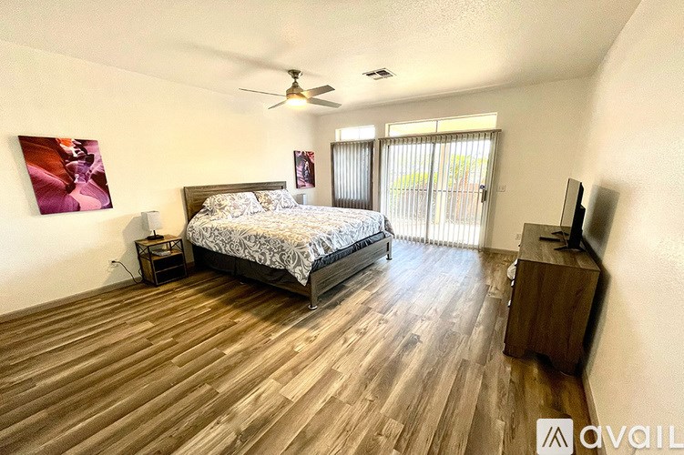 A bedroom with a large bed and wooden flooring.