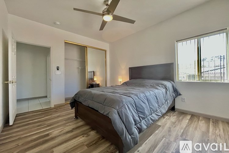 A bedroom with a bed, a ceiling fan, and a sliding glass door.