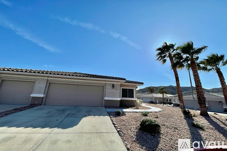 A house with a driveway and palm trees in front.