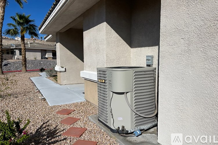 A large outdoor air conditioning unit is installed on a concrete slab outside a house.