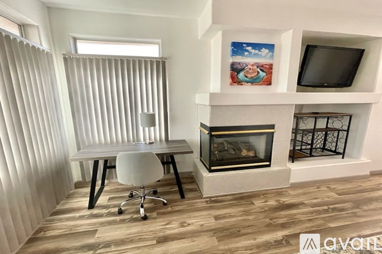 A room with a desk, chair, and fireplace.