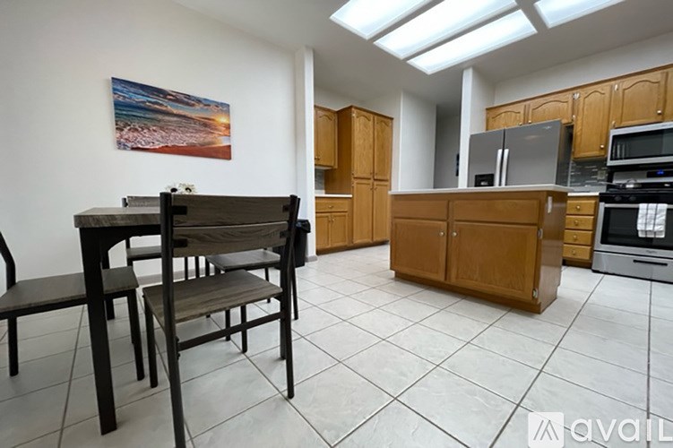 A kitchen with a table and chairs in the foreground and a painting on the wall.