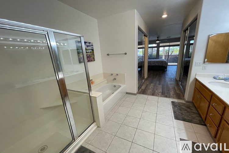 A bathroom with a glass shower door and a white bathtub.