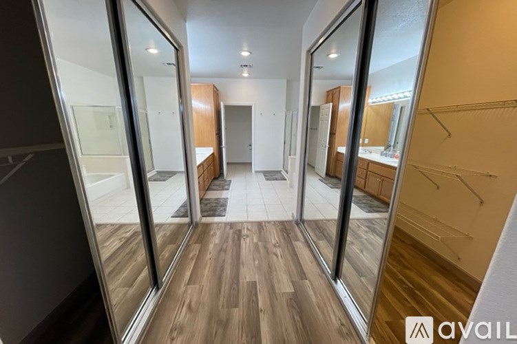 A hallway with wooden floors and glass doors leading to other rooms.
