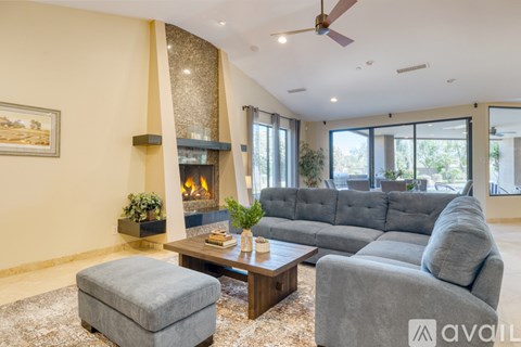 A living room with a grey couch, a fireplace, and a painting on the wall.