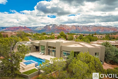 A large house with a pool in the foreground and a mountain range in the background.