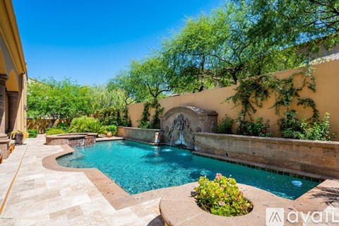 A pool with a waterfall and a stone wall.