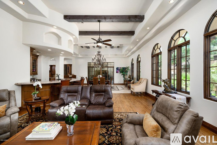 A living room with a brown leather couch and a chandelier.
