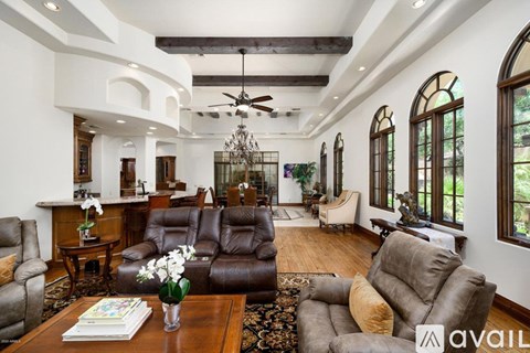 A living room with a brown leather couch and a chandelier.