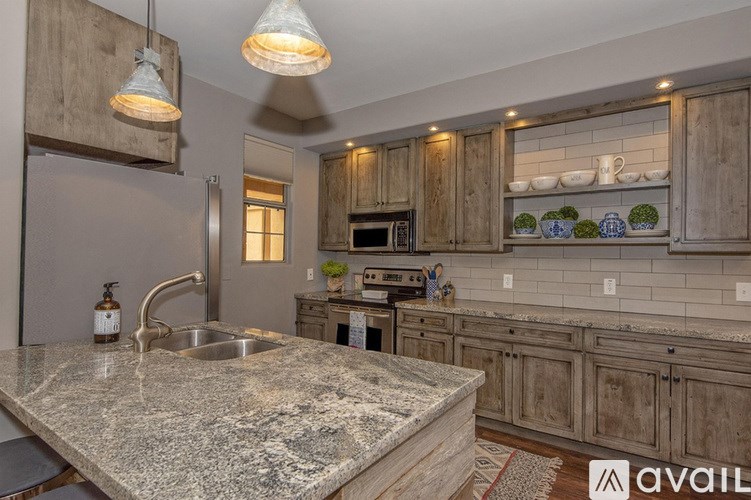 A kitchen with a marble countertop and wooden cabinets.