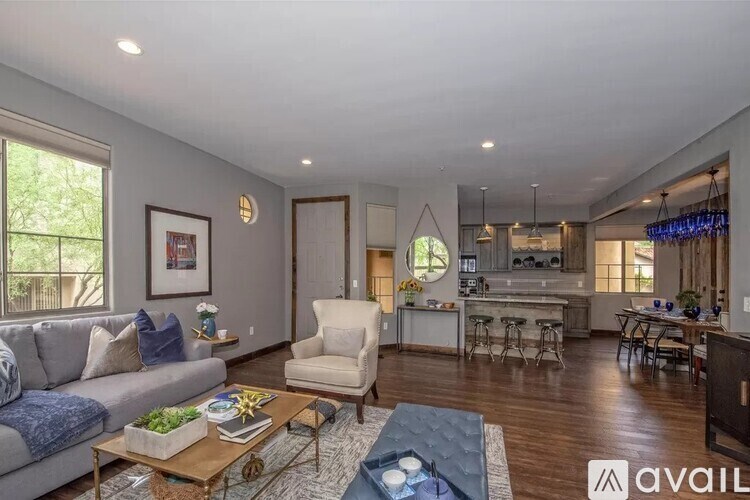 A living room with a grey couch, a coffee table, and a dining area in the background.