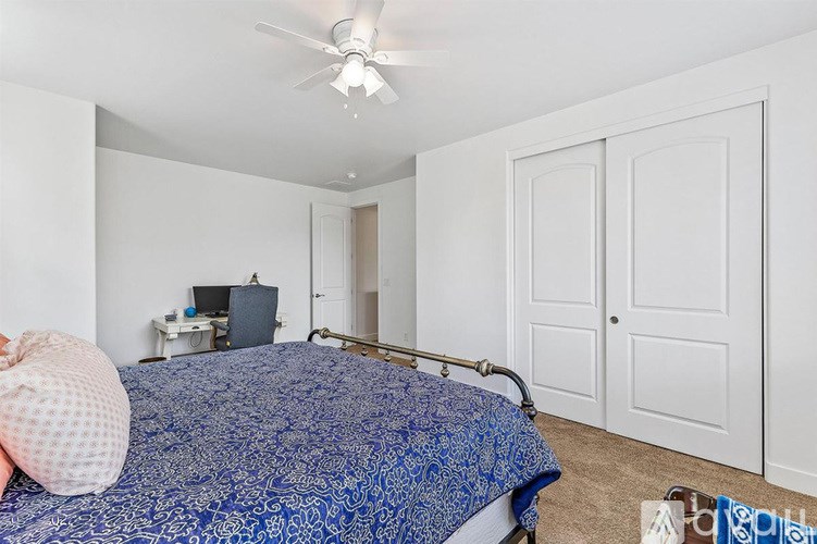 A bedroom with a bed, a ceiling fan, and a television.