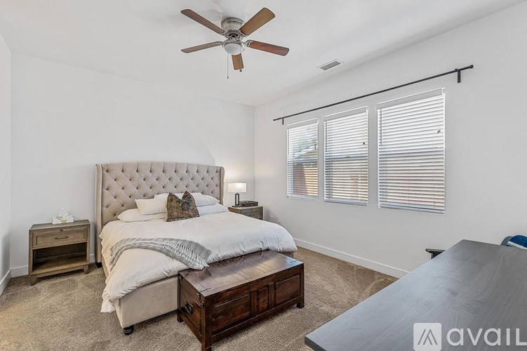 A bedroom with a large bed, a ceiling fan, and a wooden coffee table.