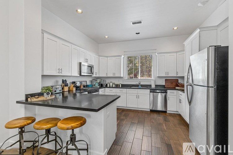 A kitchen with white cabinets and a black countertop.