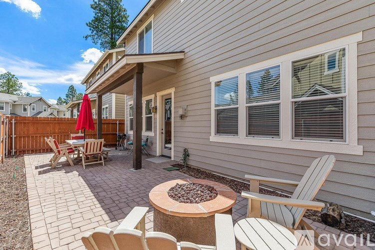 A patio with a table and chairs is in front of a house.