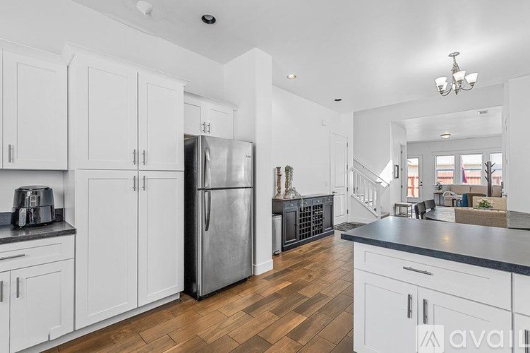 A kitchen with white cabinets and a stainless steel refrigerator.