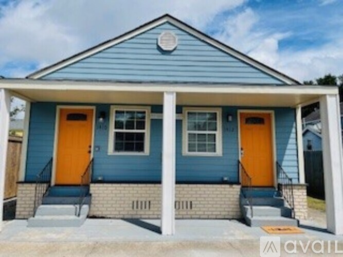 A blue house with two orange doors is for sale.