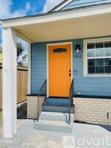A blue house with a yellow door and a window with the number 1410 on it.