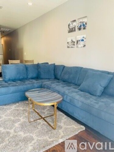 A living room with a blue couch and a gold-framed table.