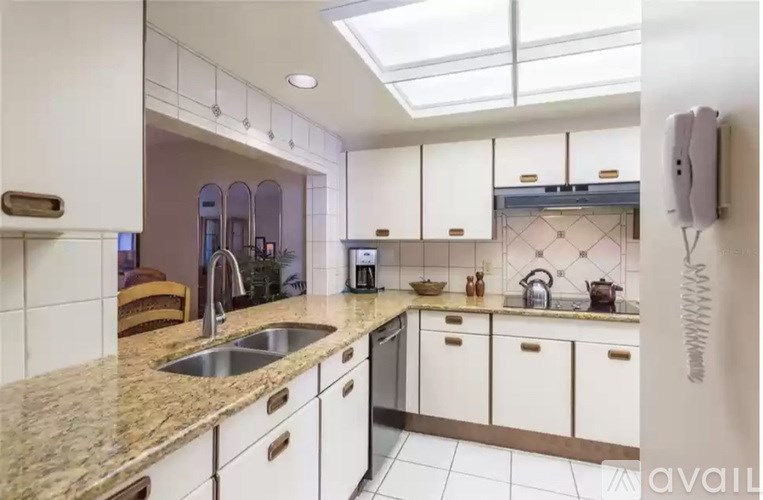 A kitchen with white cabinets and a marble countertop.