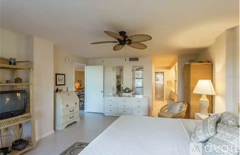 A bedroom with a large bed, a television, and a ceiling fan.