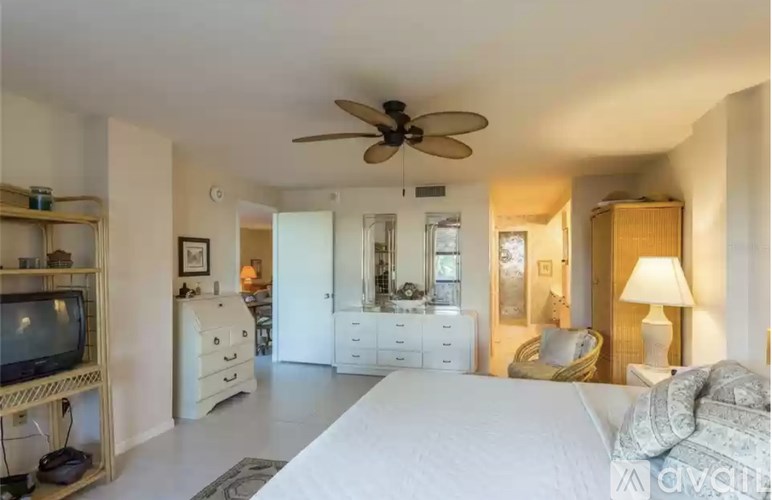 A bedroom with a large bed, a television, and a ceiling fan.