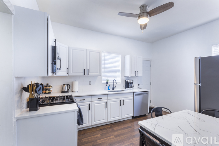 A kitchen with white cabinets and a marble table.