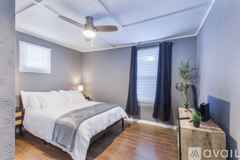 A bedroom with a bed, a ceiling fan, and a wooden dresser.