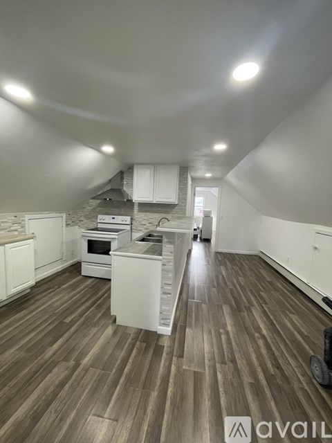 A kitchen with white cabinets and a wooden floor.